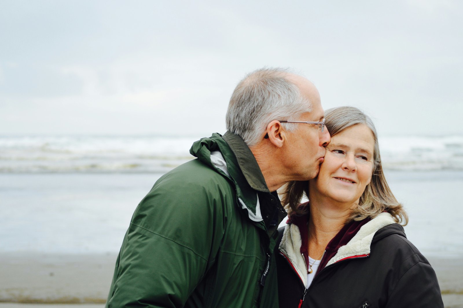 Picture of an old man giving his wife a kiss on the cheek.